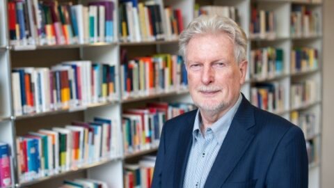 peter-voss-bibliothek Mann in Anzug steht vor einem Bücherregal in der Peter-Voss-Bibliothek.