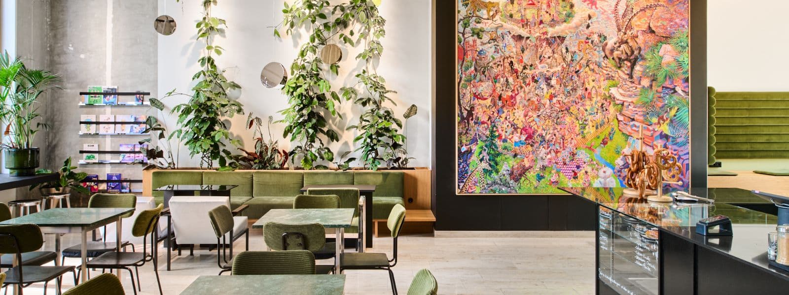 11 Moderne Café-Umgebung mit grünen Pflanzen, Tischen, Stühlen und einem bunten Wandgemälde im Hintergrund.