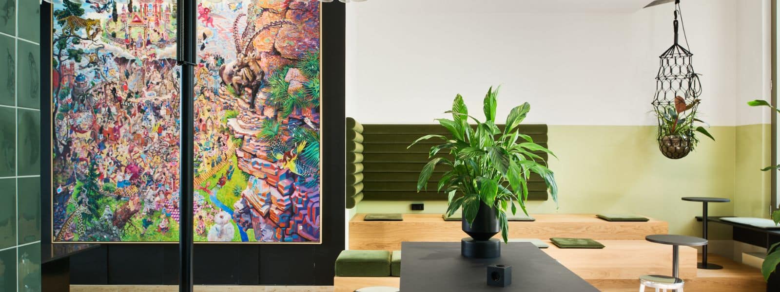 31 Buntes Wandbild in einem modernen Raum mit Pflanzen, Holztisch und grünen Sitzgelegenheiten.