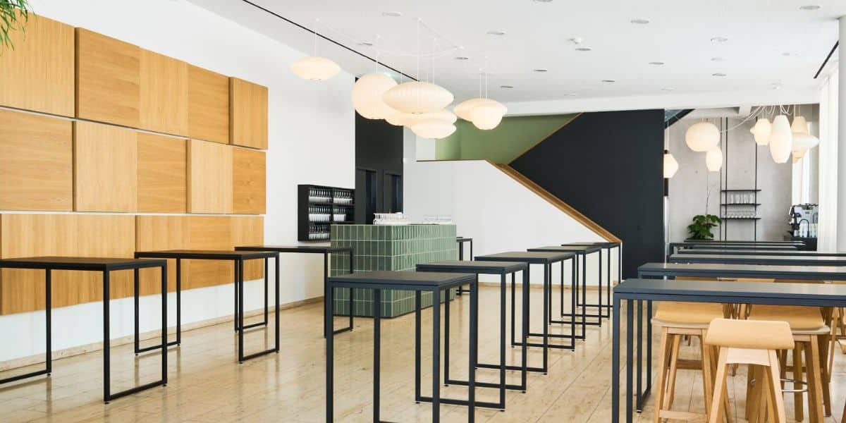 Moderne Innenansicht eines Studienzentrums mit Holzpaneelen, Stehtischen und stilvollen Lampen.